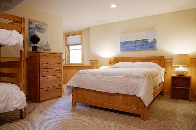Family-friendly bedroom with a queen bed and an adjacent bunk bed for extra guests. Features light wood furniture, soft carpet, and nautical-themed art.