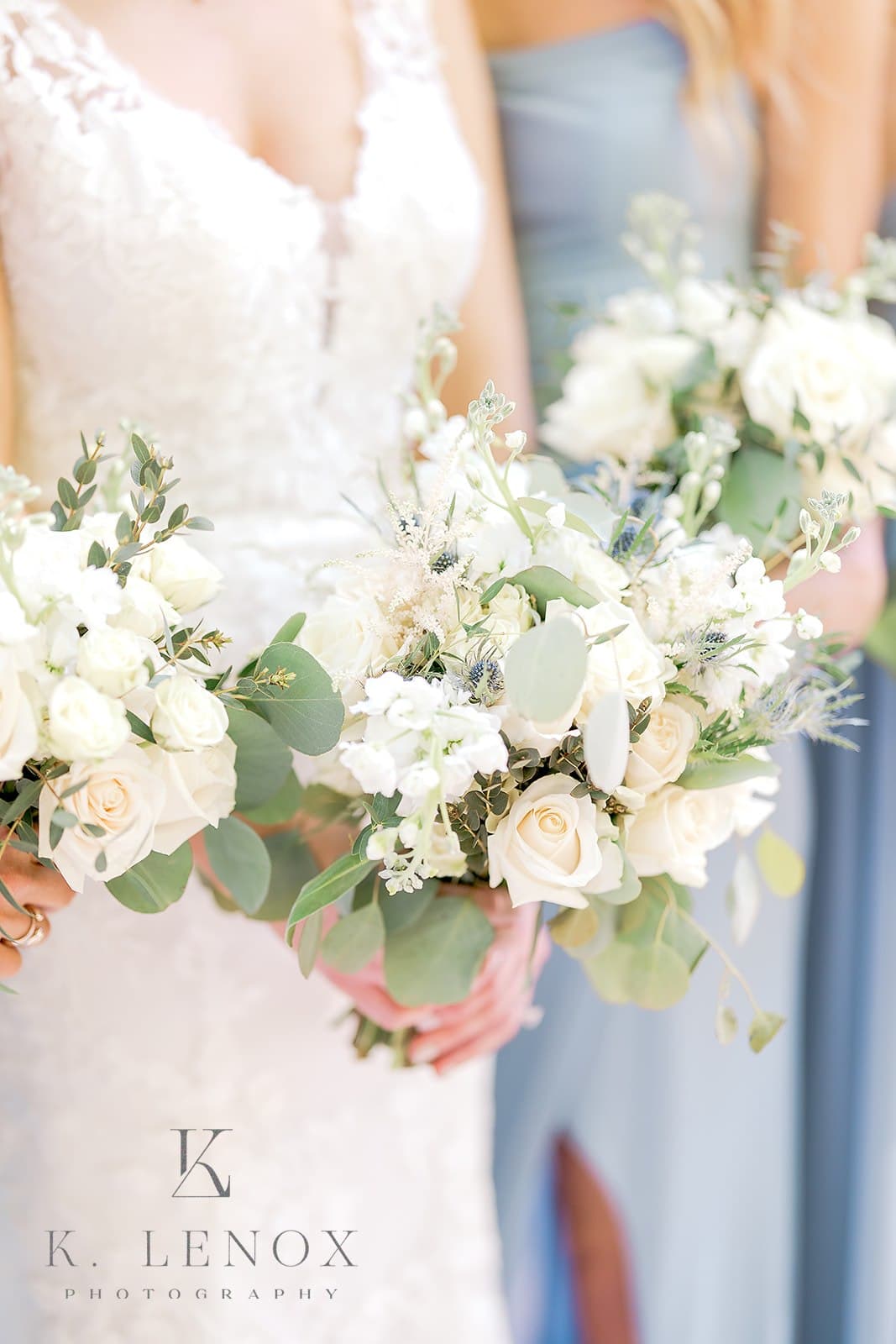 A close-up of bridesmaids holding elegant bouquets of white roses and greenery.