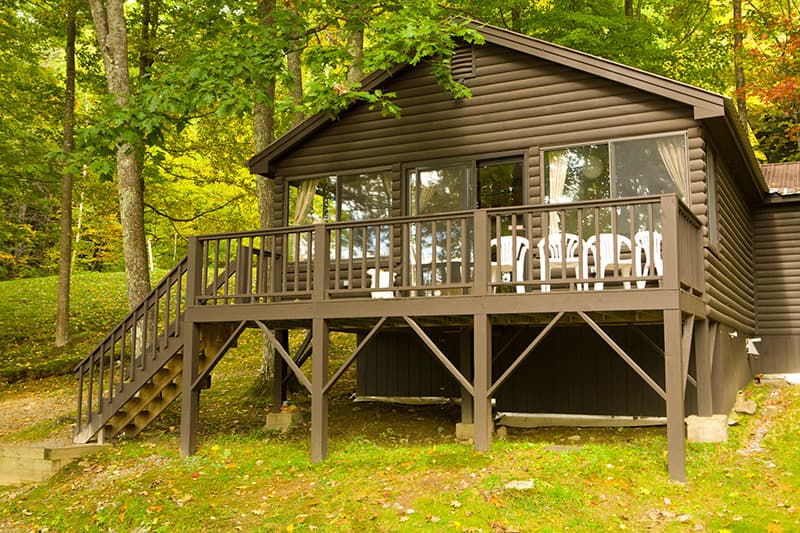 A rustic cabin with a wooden deck surrounded by trees.