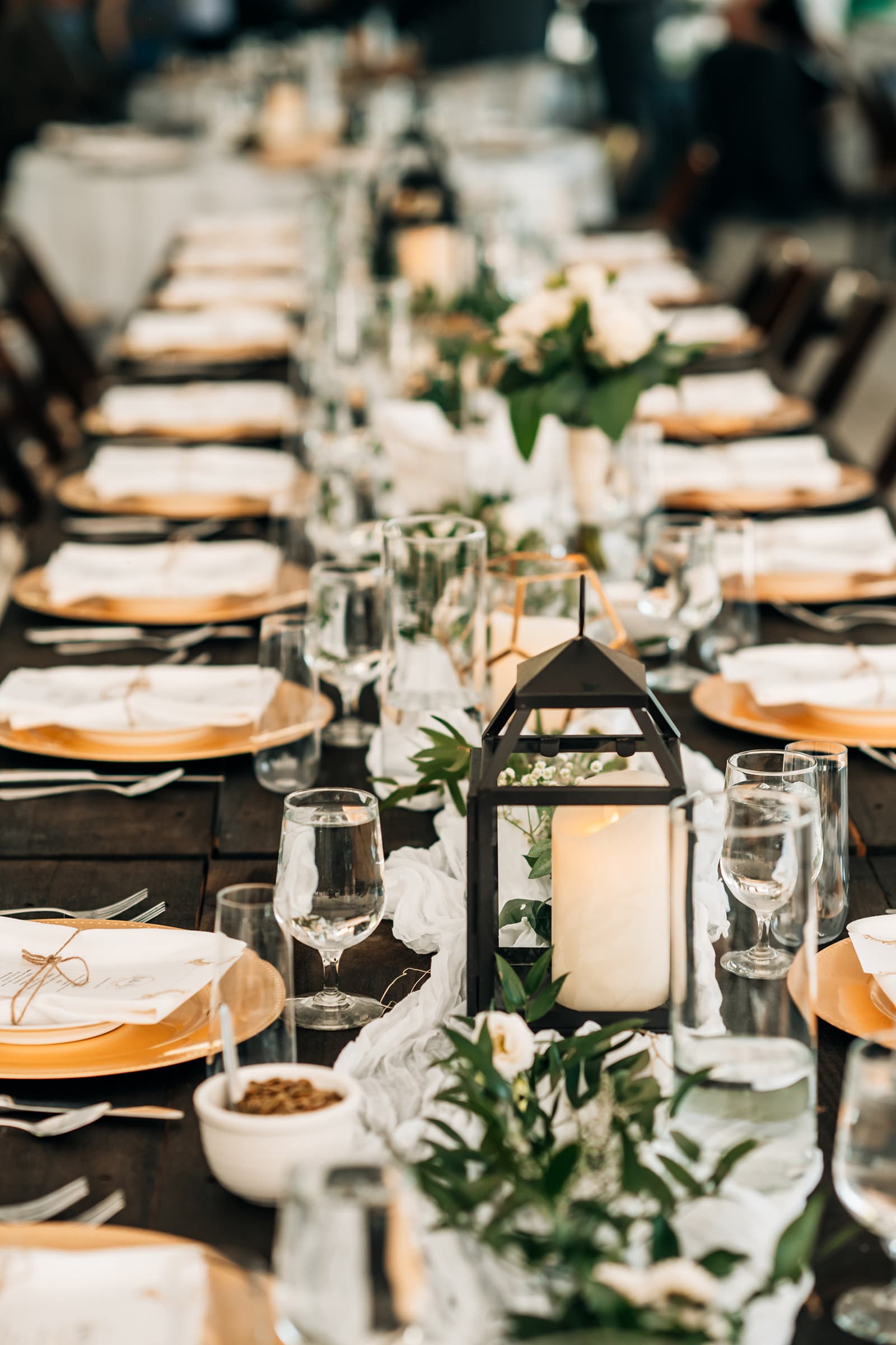 A beautifully set dining table with elegant plates, glasses, and floral arrangements.
