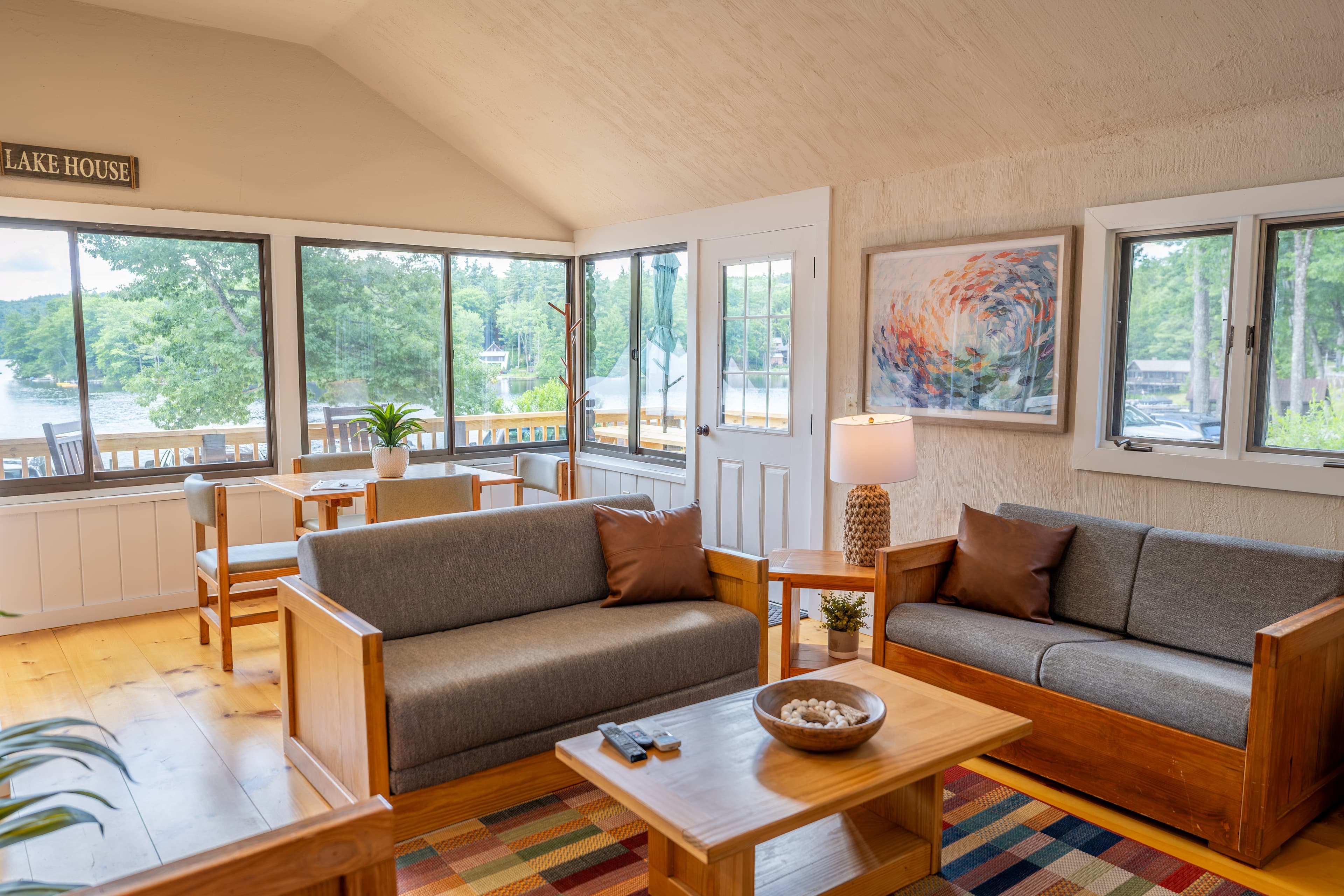 A rustic cabin living and dining area with a vaulted ceiling and large windows with a view.
