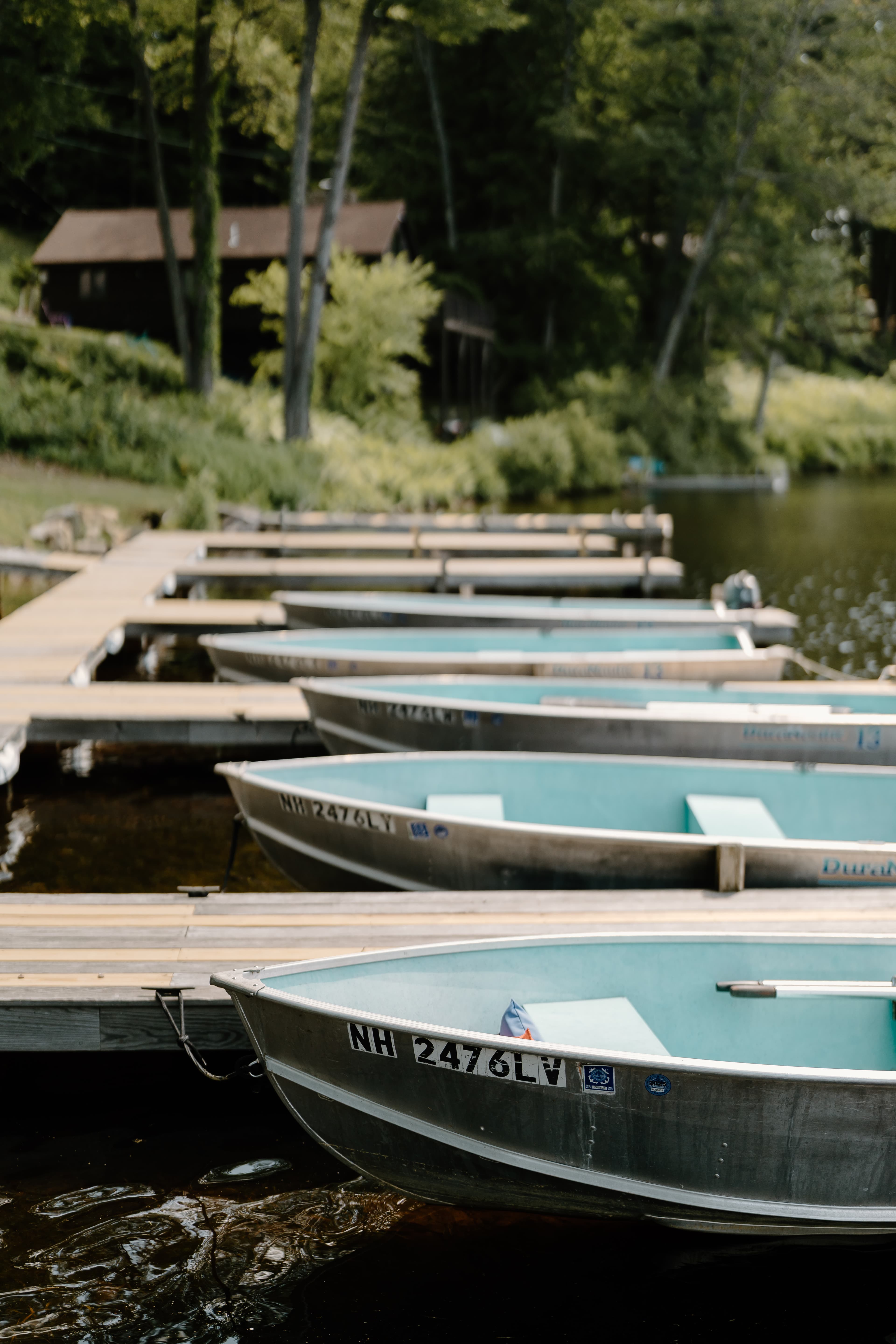 Metal boats lined up at a wooden dock by a calm waterway. Metal boats lined up at a wooden dock by a calm waterway.